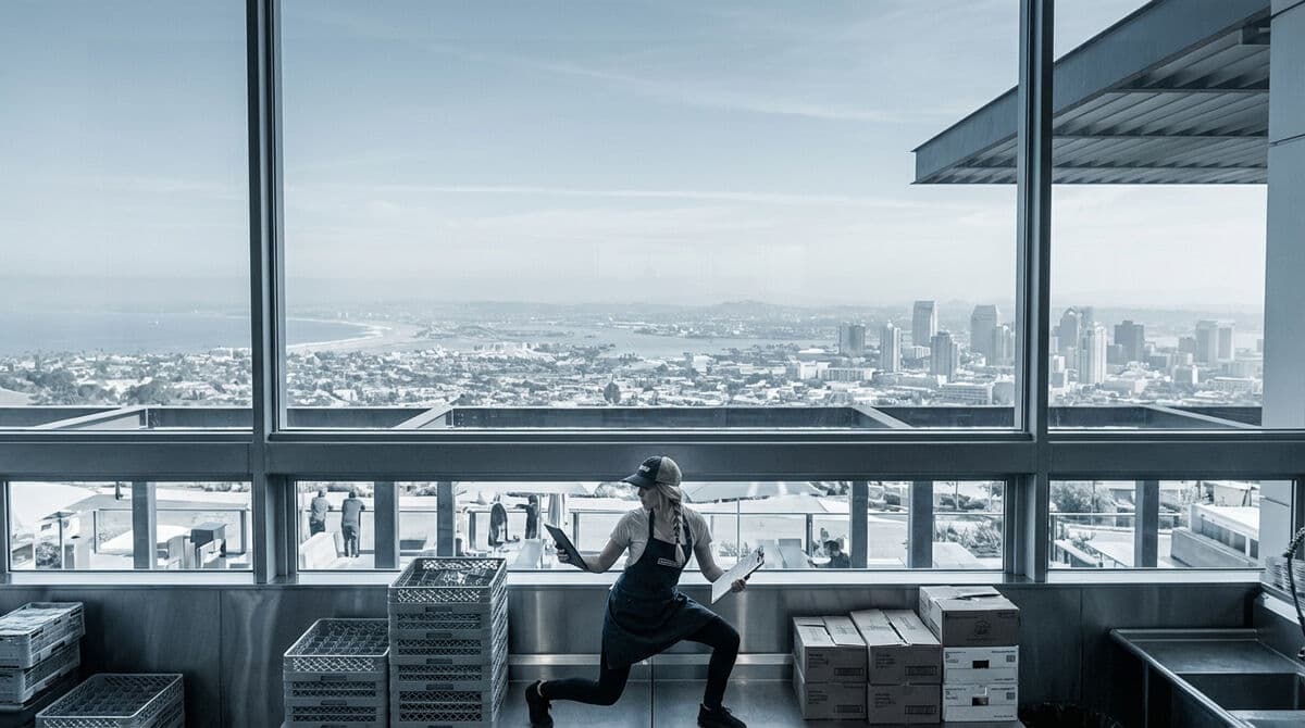 Franchise operator sitting on rooftop patio reviewing data on tablet with city skyline view
